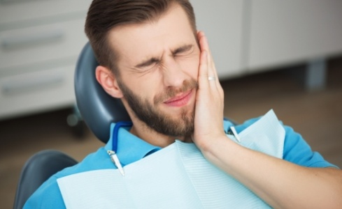 Man in need of emergency dentistry holding jaw in pain