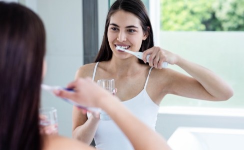 Woman brushing teeth to prevent dental emergencies