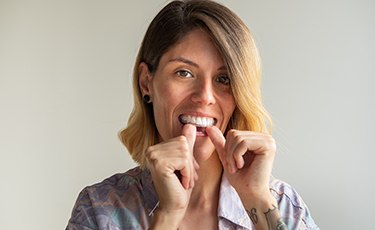 Woman putting on Invisalign tray 