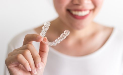 Woman holding an Invisalign clear braces tray