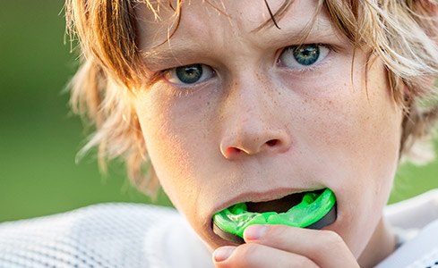 Teen placing mouthguard after preventive dentistry checkup and teeth cleaning