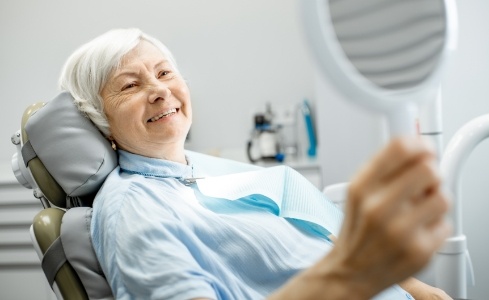 Woman looking at smile after one visit dental restoration
