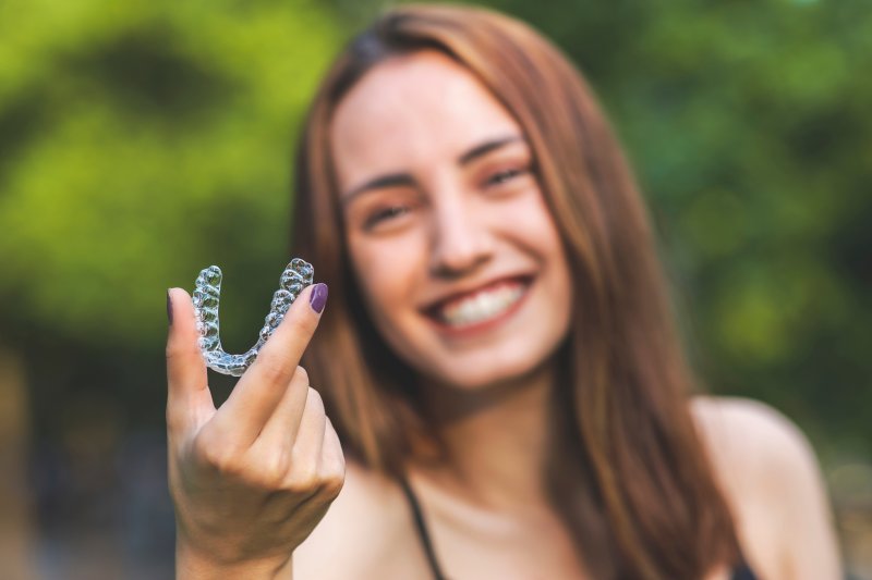 A blurred woman holding an Invisalign tray