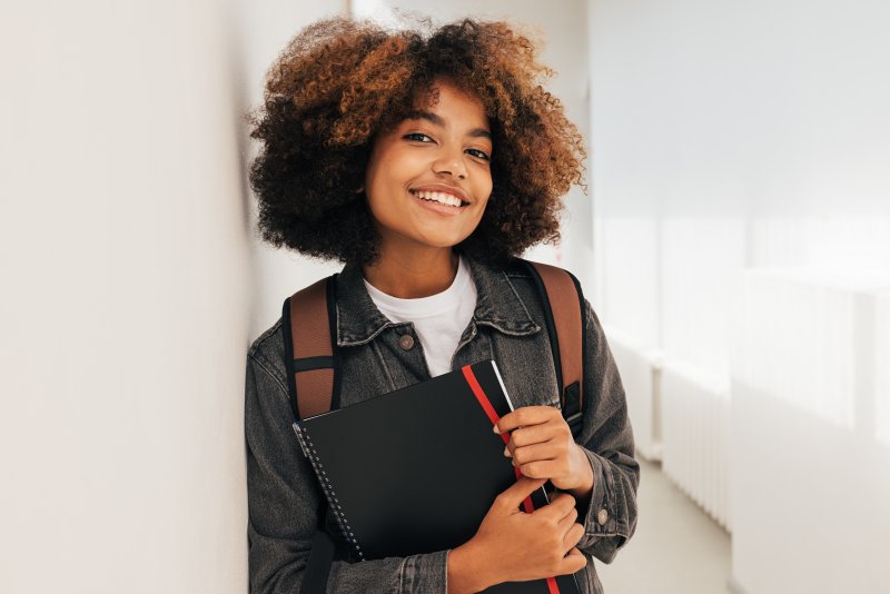 A female student leaning against a wall and looking at the camera