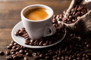 an espresso shot on a table with an open bag of coffee beans