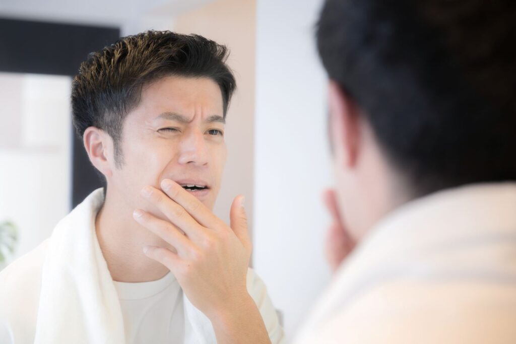A man looking at his teeth in the mirror